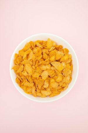 few corn flakes in white big bowl on light pink