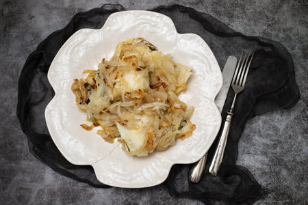 fried cod fish with onion and olive oil on white plateの写真素材