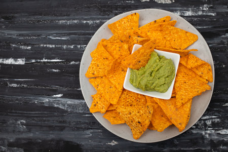 orange mexican nachos chips and guacamole on white small plateの写真素材