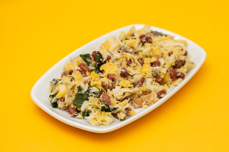 cod fish with corn bread, spinach and boiled beans on white dishの写真素材