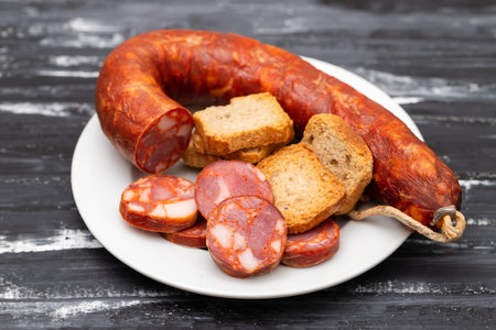 typical portuguese smoked sausage chourico and toasts on white plate