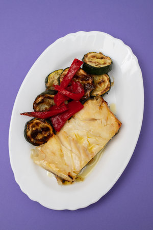 Fish dish - fried cod fish with grilled vegetables in white plate