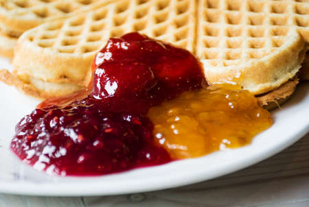 berry jam in assortment and fresh Norwegian waffles on a plate.close-up.Selective focus.