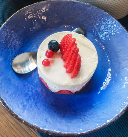 dessert with strawberries on a dark blue ceramic plateの写真素材