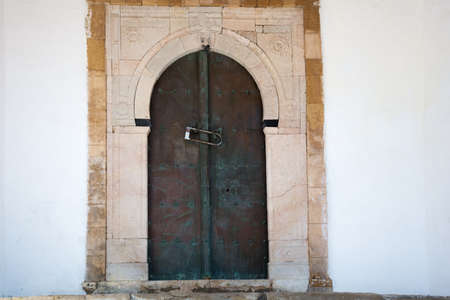 Ancient, metal door with an arch and stonework. Sidi Bou Said. Tunisia.Maghreb styleの写真素材