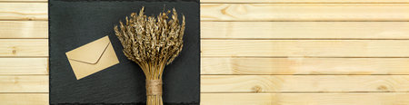 Wheat bouquet with kraft letter on wooden background bannerの写真素材