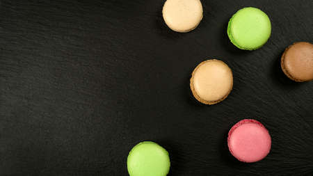 Multicolored macarons on black background with copy space top viewの写真素材