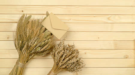 Lots of craft envelopes and a two bouquet of wheat on a wooden background
