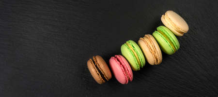 Multicolored cakes on a black background with copy space