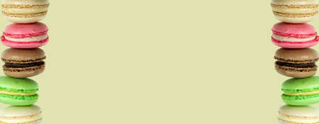 Two stacks of multicolored macaroon cakes on a milky cream background and in the middle of a copy spaceの写真素材