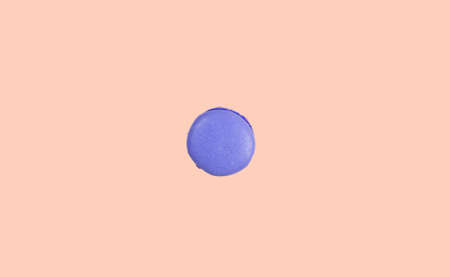 One purple macaroon like button in the center of peach color backgroundの写真素材