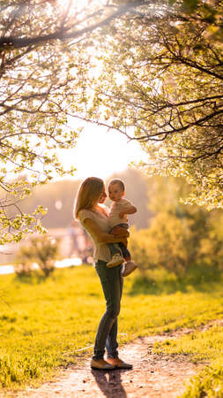 Silhouettes of mom and baby in the shade of treesの写真素材