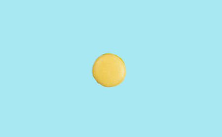 Minimalistic summer background with yellow macaroon cake in the center of the blue background symbolizing the sunの写真素材