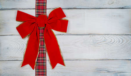 Red bow on a wooden light background, Christmas background, photo for a postcard or gift bagの写真素材