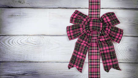 Pink bow on a wooden light background, Christmas background, photo for a postcard or gift bagの写真素材