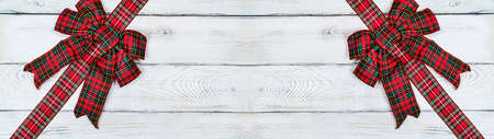 Two red Christmas bows on a light wooden background banner. Christmas background, photo for a postcard or gift bagの写真素材