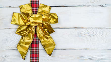 Bows on a banner, gold bows on a ribbon on a wooden light background banner with copy spaceの写真素材