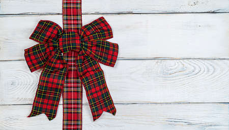 Red bow on a wooden light background, Christmas background, photo for a postcard or gift bagの写真素材