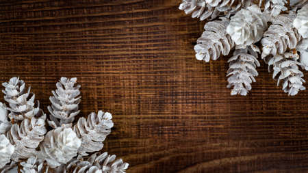 Beautifulframe of white cones on a brown wooden table, christmas winter background with copy spaceの写真素材
