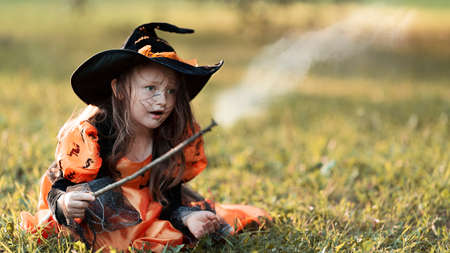Little witch girl conjures magic wand on Halloween.の写真素材