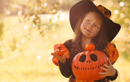 Pumpkin head Jack-o-lantern in the hands of a girl in a witch costume on Outdoors with a copy space, background for Halloweenの写真素材