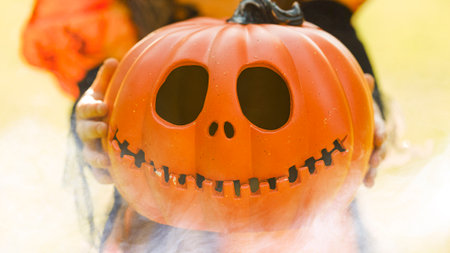 Pumpkin head Jack-o-lantern in the hands of a girl in a witch costume , close-up background for Halloweenの写真素材