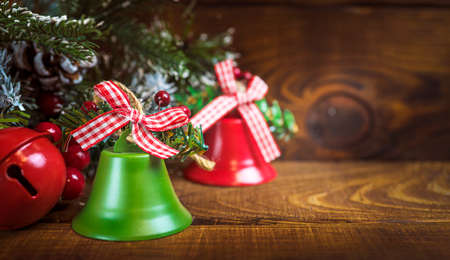 Christmas bells on a wooden table near a christmas tree, christmas winter background with copy spaceの写真素材