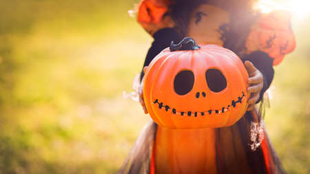 Pumpkin head Jack-o-lantern in the hands of a girl in a witch costume , close-up background for Halloweenの写真素材