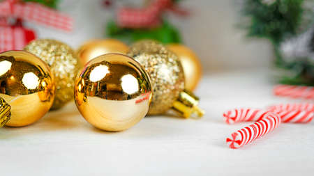 Christmas background with copy space, golden Christmas decorations and striped lollipops on a white table with bokeh and holiday and magic atmosphere, suitable for postcards and gift bagsの写真素材