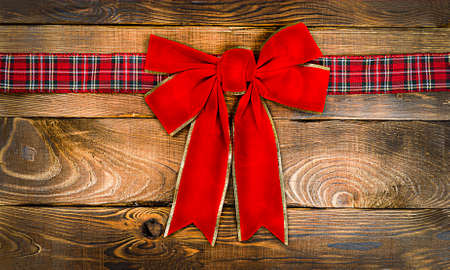 red Christmas bow on a wooden background. Christmas background, photo for a postcard or gift bagの写真素材