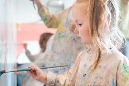 Little child draws with paints on a white wall, side viewの写真素材