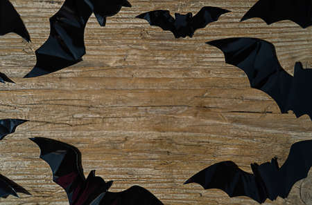 Big and small black bats on a wooden background with copy space in the centerの写真素材