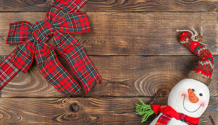 Christmas toy snowman with christmas bow on wooden background with copy space, front view for postcards and gift bagsの写真素材