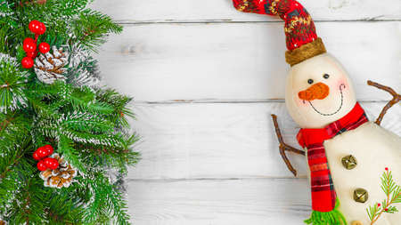 Christmas toy snowman and spruce branches on white wooden background with copy space, front view for postcards and gift bagsの写真素材
