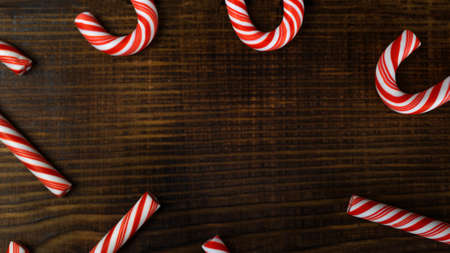 Christmas striped canes lollipops on a brown textured wooden background with copy space, see from aboveの写真素材