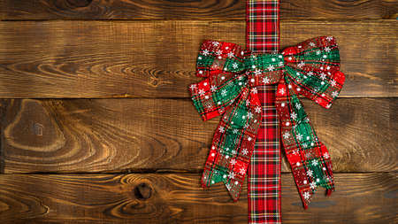 red Christmas bow on a wooden background. Christmas background, photo for a postcard or gift bagの写真素材