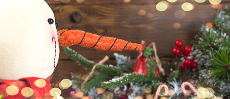 Christmas toy snowman and spruce branches on wooden background with copy space, front view for postcards and gift bagsの写真素材