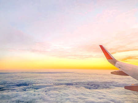 Airplane wing in the sky at beautiful sunset, airplane flight in the sky with copy spaceの写真素材