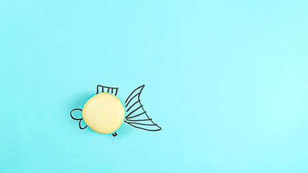 Small fish macaroon cake on a blue background concept with copy space