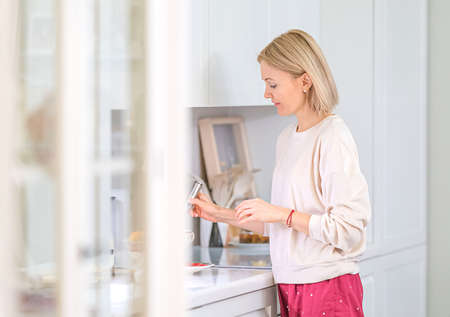 Young beautiful blonde girl at home in the kitchenの写真素材