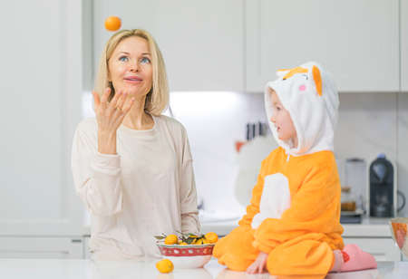 Mom and little daughter are preparing breakfast in the kitchenの写真素材