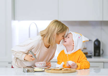 Mom and little daughter are preparing breakfast in the kitchenの写真素材