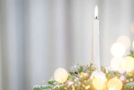 Burning white candle with Christmas tree decoration and spruce branch with copy spaceの写真素材