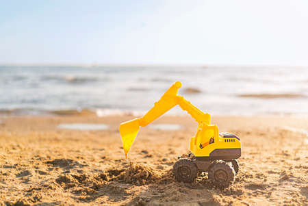 Toy excavator on the beach with copy spaceの写真素材