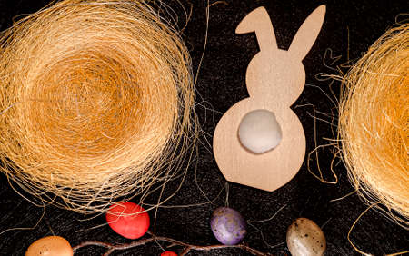 Easter background top view with rabbit, painted eggs, nests on dark background