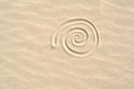 Spiral shell drawn on the sand on the beach top view with copy spaceの写真素材