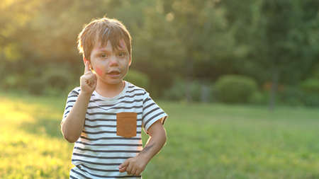 Portrait of a little boy who raised his finger up, photo in nature with copy spaceの写真素材
