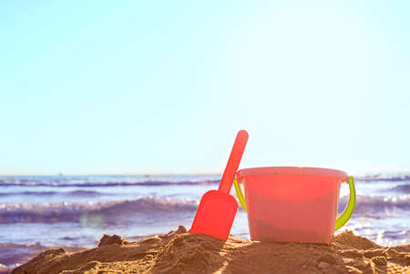 Plastic baby pink bucket with a shovel on the sand on the beach by the sea on a sunny day with copy spaceの写真素材