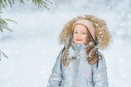 A beautiful blue-eyed girl smiles in winter, a portrait of a childの写真素材