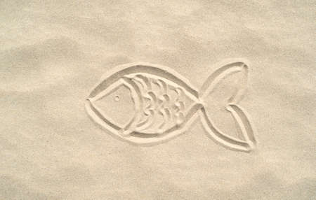 Silhouette of a fish painted on the sandの写真素材